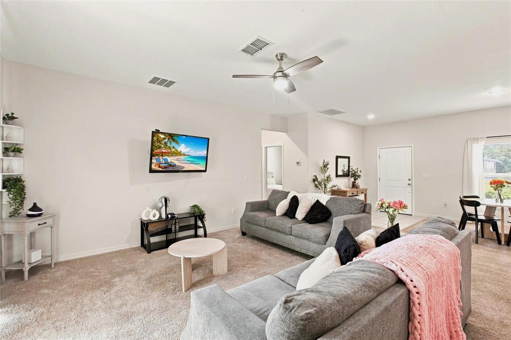 A living room features gray sofas, a wall-mounted television, and a ceiling fan — 5724 BANNOCK CIRCLE, NORTH PORT, FL