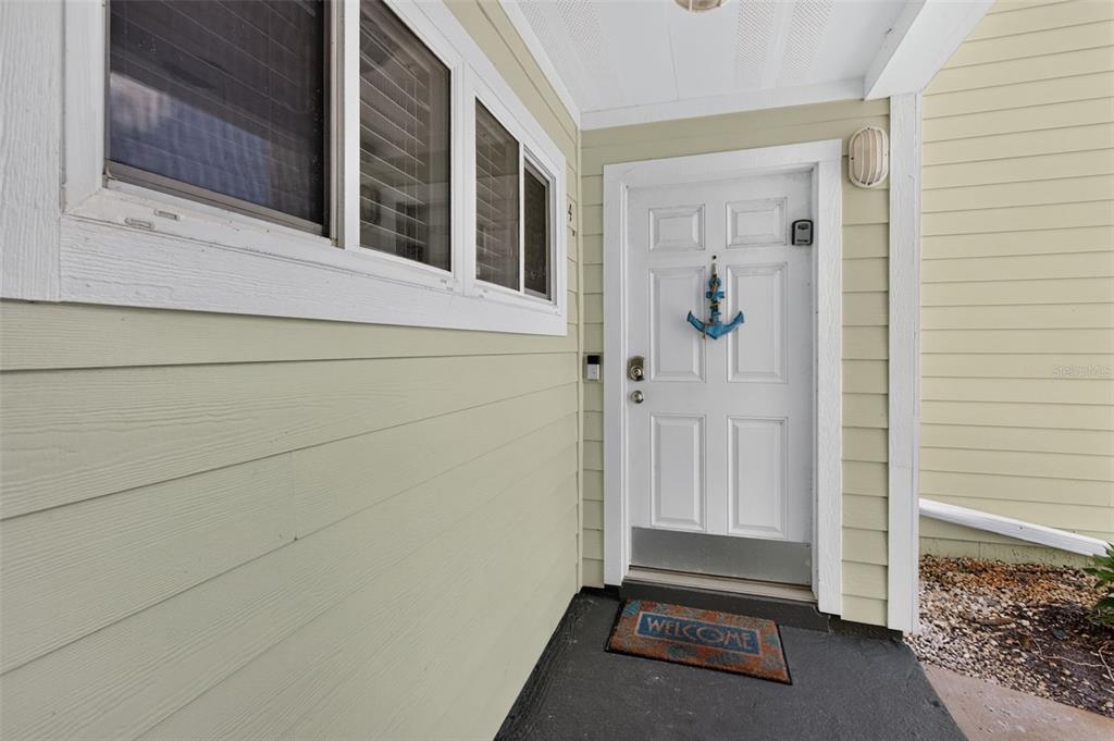 A white front door with an anchor decoration sits on a porch with light-colored siding — 6300 A1A S UNIT A44D, ST AUGUSTINE, FL