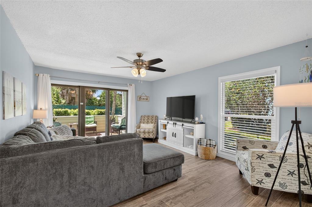 A living room features a gray sectional sofa, a television on a white console, and chairs — 6300 A1A S UNIT A44D, ST AUGUSTINE, FL