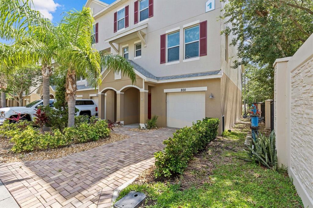 A three-story townhouse exterior features a paved driveway, a single-car garage, and palm trees — 800 CALLISTA CAY LOOP, TARPON SPRINGS, FL
