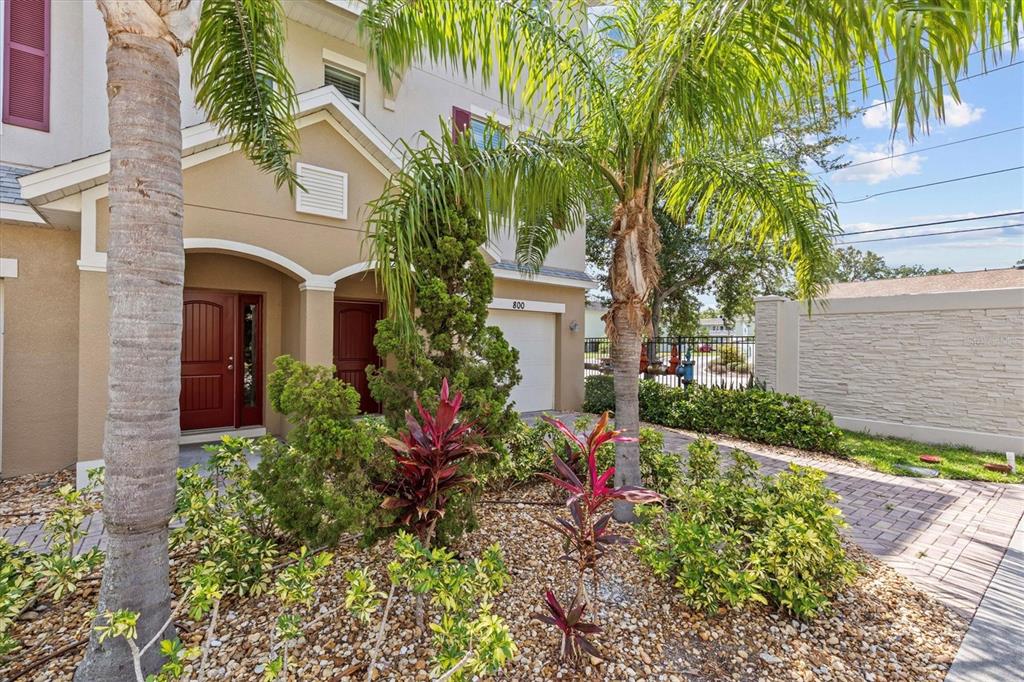 The exterior of a two-story tan townhouse features a red front door and palm trees — 800 CALLISTA CAY LOOP, TARPON SPRINGS, FL