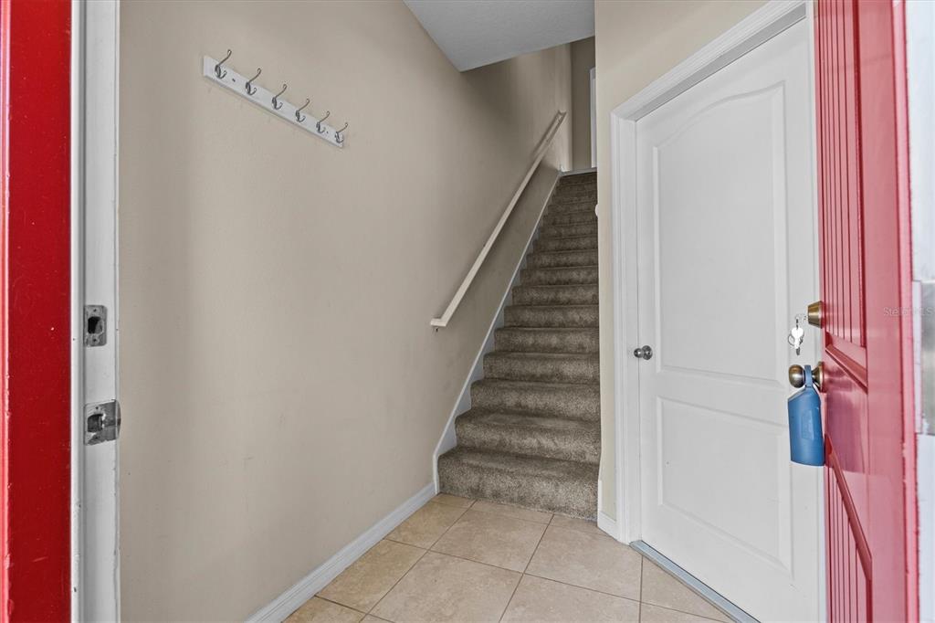An entryway features a tiled floor, a carpeted staircase with a handrail, and wall-mounted hooks — 800 CALLISTA CAY LOOP, TARPON SPRINGS, FL