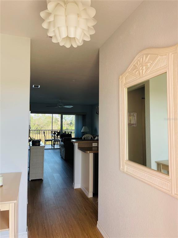 A hallway with a decorative light fixture and wall mirror leads into an open-concept living area — 2040 WILLOW HAMMOCK CIRCLE UNIT 202, PUNTA GORDA, FL