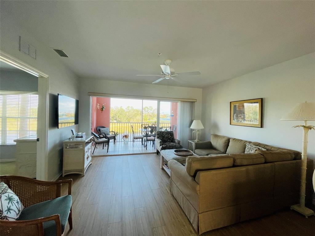 A living room features wood-look flooring, a sectional sofa, and a sliding door to a balcony — 2040 WILLOW HAMMOCK CIRCLE UNIT 202, PUNTA GORDA, FL