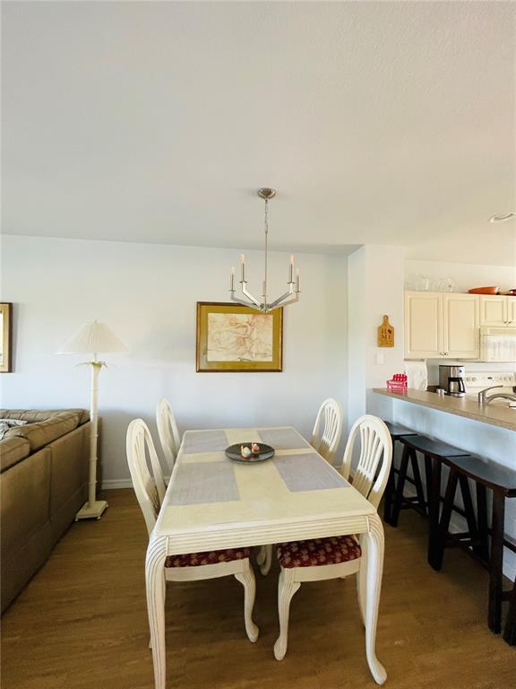 A dining area features a light-colored table with four chairs under a modern chandelier — 2040 WILLOW HAMMOCK CIRCLE UNIT 202, PUNTA GORDA, FL