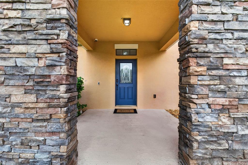 A blue front door sits under a covered entryway flanked by two stone pillars — 810 WOODS LANDING DRIVE, MINNEOLA, FL