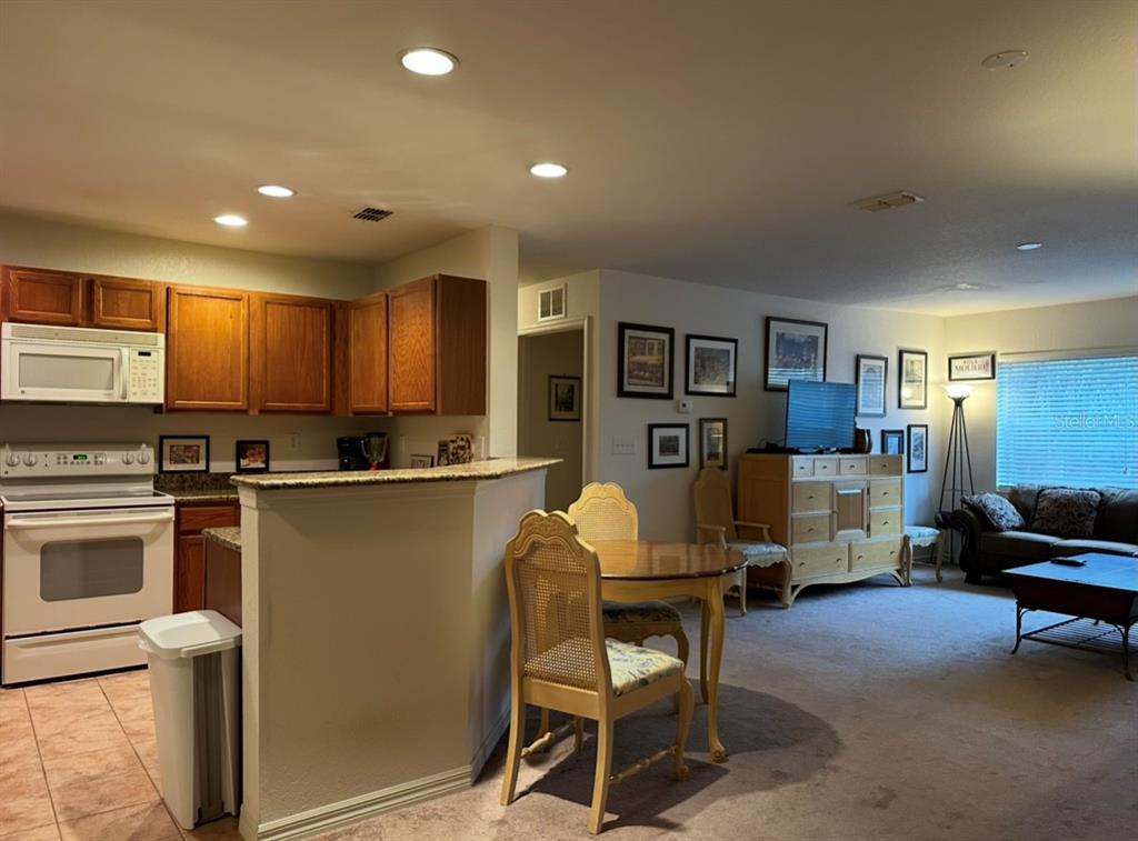A kitchen with wood cabinets and a breakfast bar opens into a carpeted dining area — 4600 E MOODY BOULEVARD UNIT 3J, BUNNELL, FL