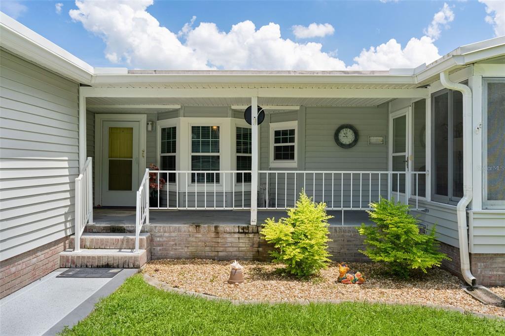 A covered porch with a white railing sits in front of a house with siding — 705 OAK BOULEVARD, WILDWOOD, FL