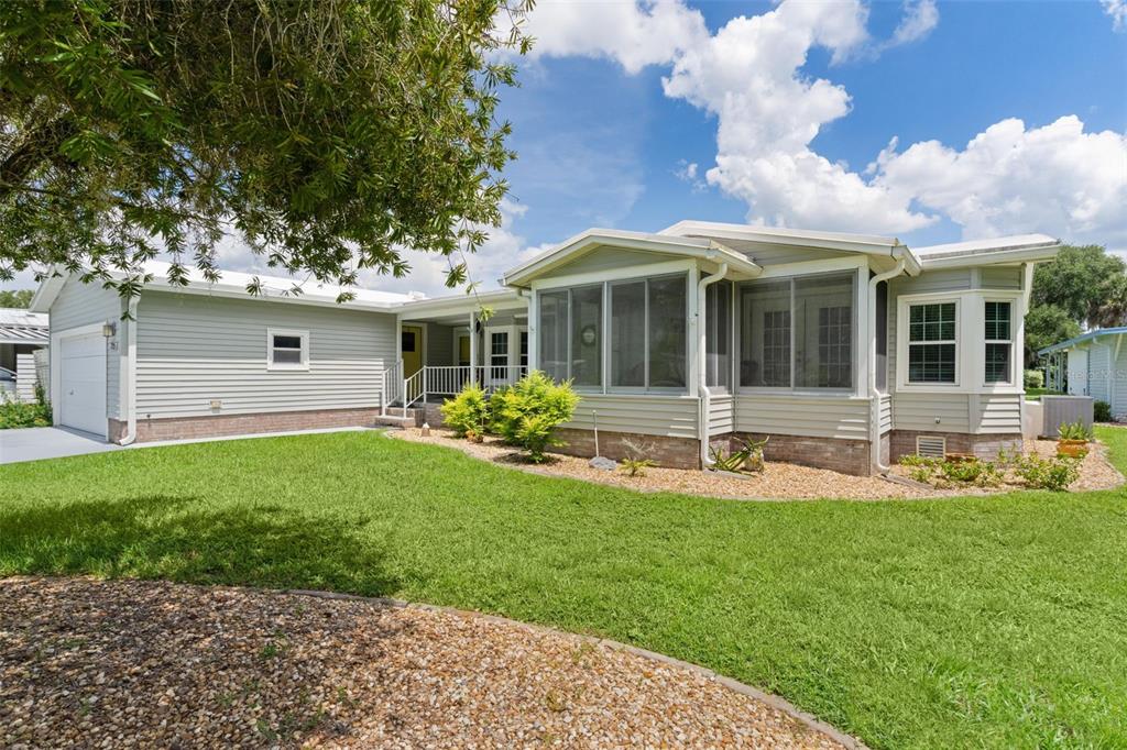 A light gray house with a garage, a screened-in porch, and a landscaped front yard — 705 OAK BOULEVARD, WILDWOOD, FL