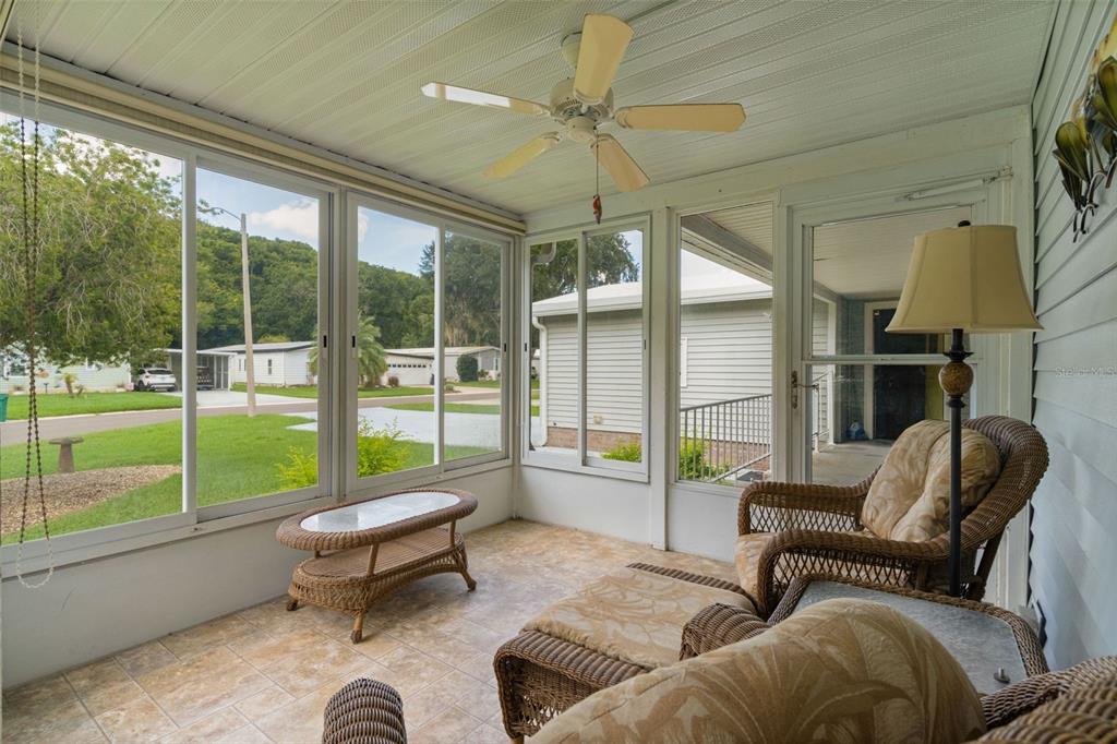 A sunroom with tile flooring, wicker furniture, a ceiling fan, and large windows overlooking outdoors — 705 OAK BOULEVARD, WILDWOOD, FL