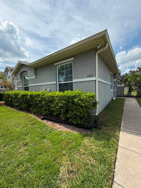 The exterior of a gray house features a green hedge and a concrete sidewalk — 13121 SUMMERTON DRIVE, ORLANDO, FL