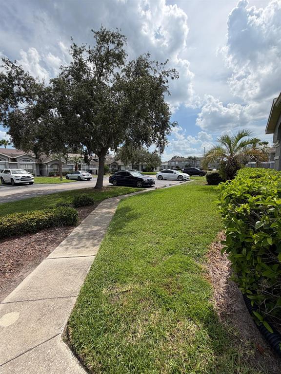 A sidewalk leads past a grassy lawn and a large tree toward parked cars — 13121 SUMMERTON DRIVE, ORLANDO, FL