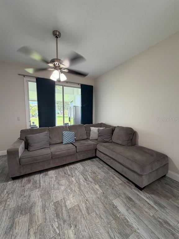 A living room features a grey sectional sofa, wood-look tile flooring, and a ceiling fan — 13121 SUMMERTON DRIVE, ORLANDO, FL