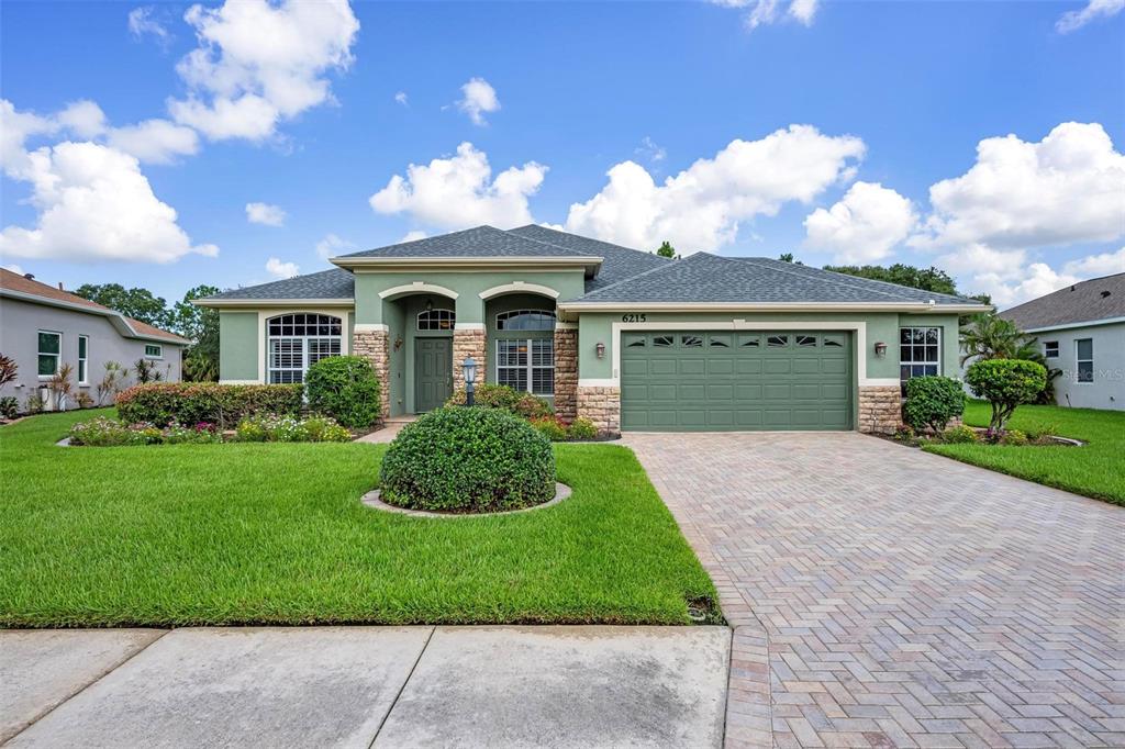 A single-story house with a green exterior, stone accents, and a paved driveway — 6215 90TH AVENUE CIRCLE E, PARRISH, FL