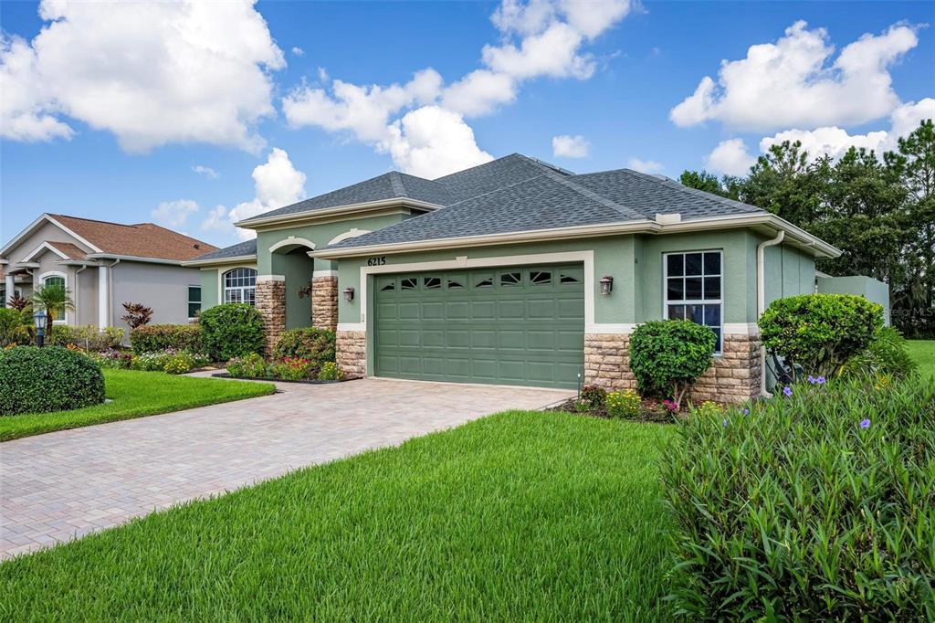 A green, single-story house with a stone-accented facade and a two-car garage — 6215 90TH AVENUE CIRCLE E, PARRISH, FL
