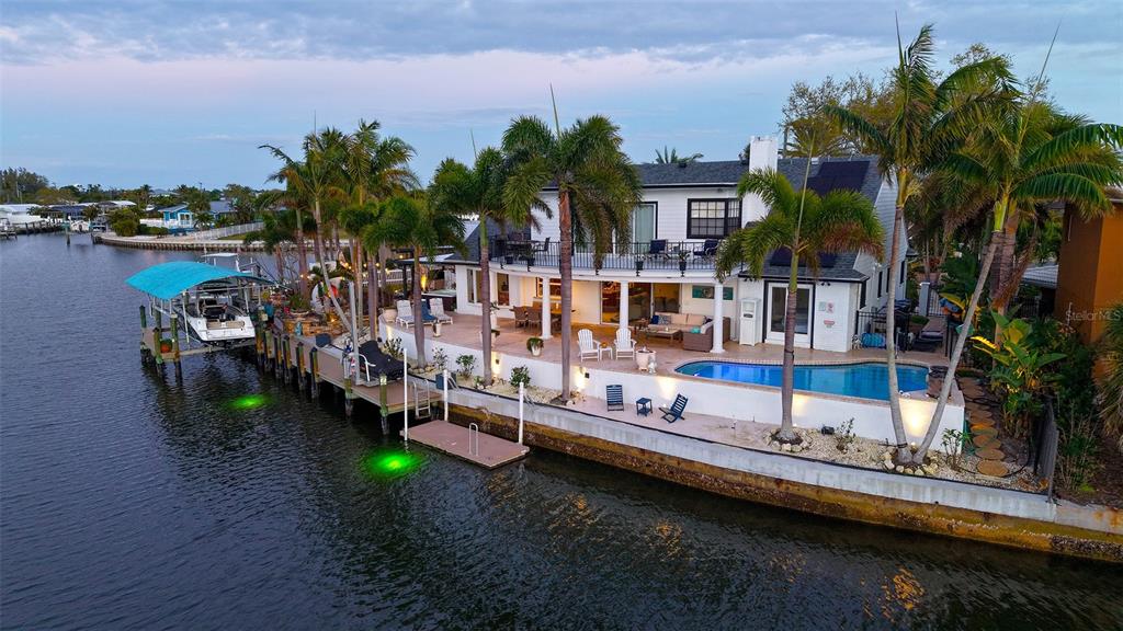 An aerial view of a waterfront house with a pool, boat dock, and palm trees — 10432 SPOONBILL ROAD W, BRADENTON, FL