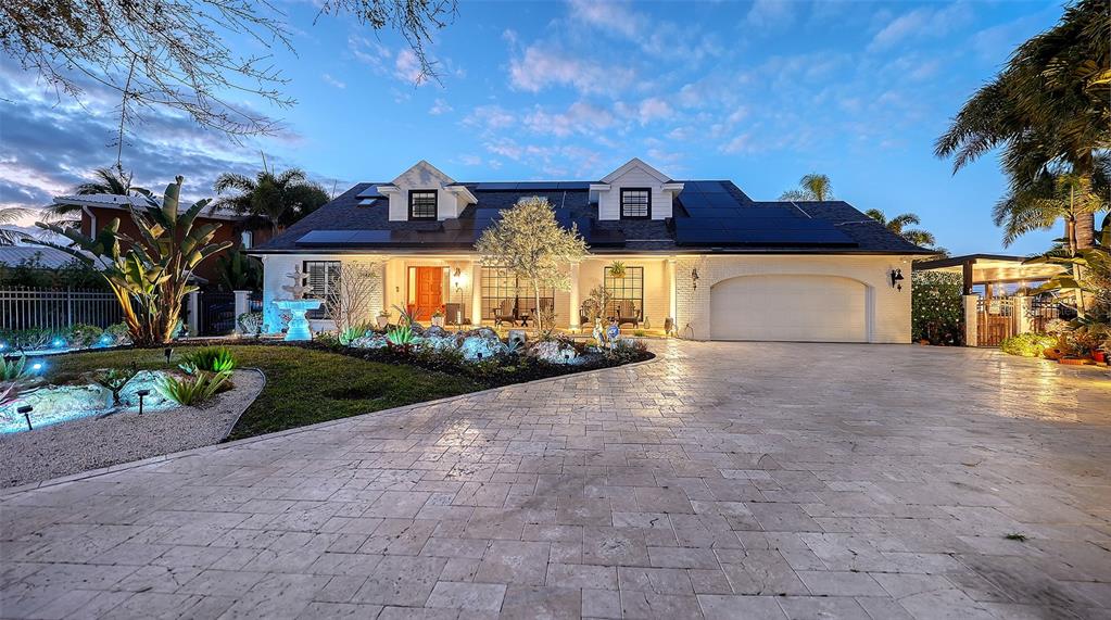 A white brick house with a paved driveway, solar panels, and a landscaped front yard — 10432 SPOONBILL ROAD W, BRADENTON, FL