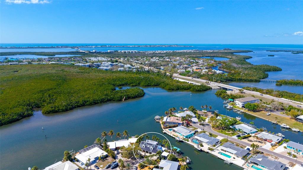 An aerial view shows a waterfront house with a pool, circled in a residential neighborhood — 10432 SPOONBILL ROAD W, BRADENTON, FL