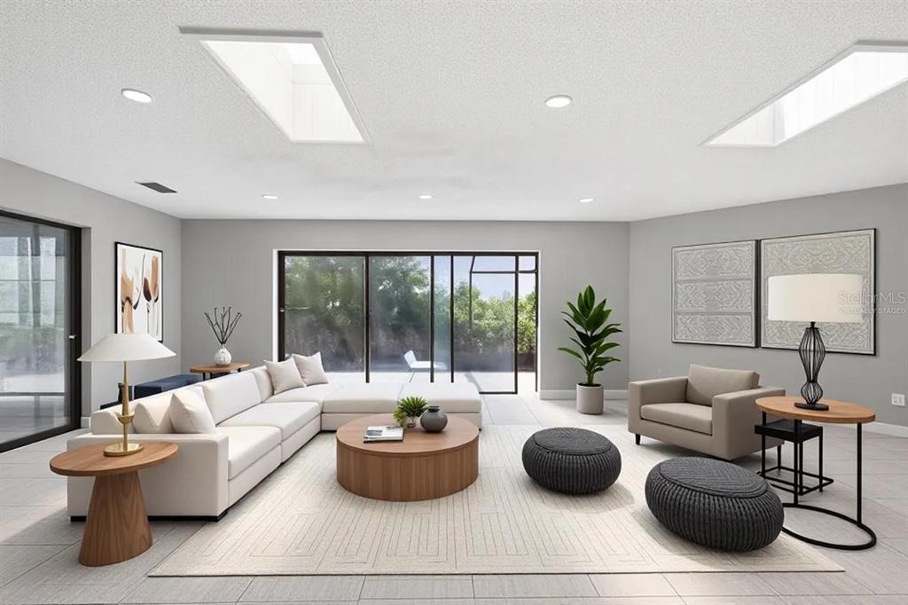 A living room with a large sectional, two skylights, and sliding glass doors to the patio — 7010 SOUTHWIND DRIVE, HUDSON, FL