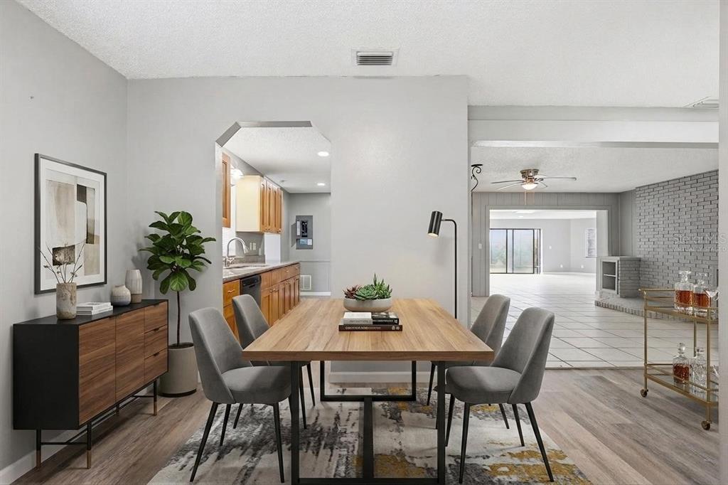 A dining room with a wooden table, gray chairs, and an adjacent kitchen opening — 7010 SOUTHWIND DRIVE, HUDSON, FL