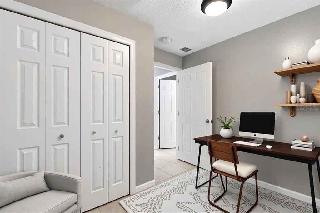 A home office with a desk, chair, closet, and wall shelving on a gray wall — 7010 SOUTHWIND DRIVE, HUDSON, FL