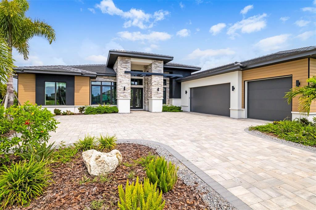 A modern single-story house features a stone-accented entryway, a paved driveway, and a three-car garage — 4116 BUTTE TRAIL, BRADENTON, FL