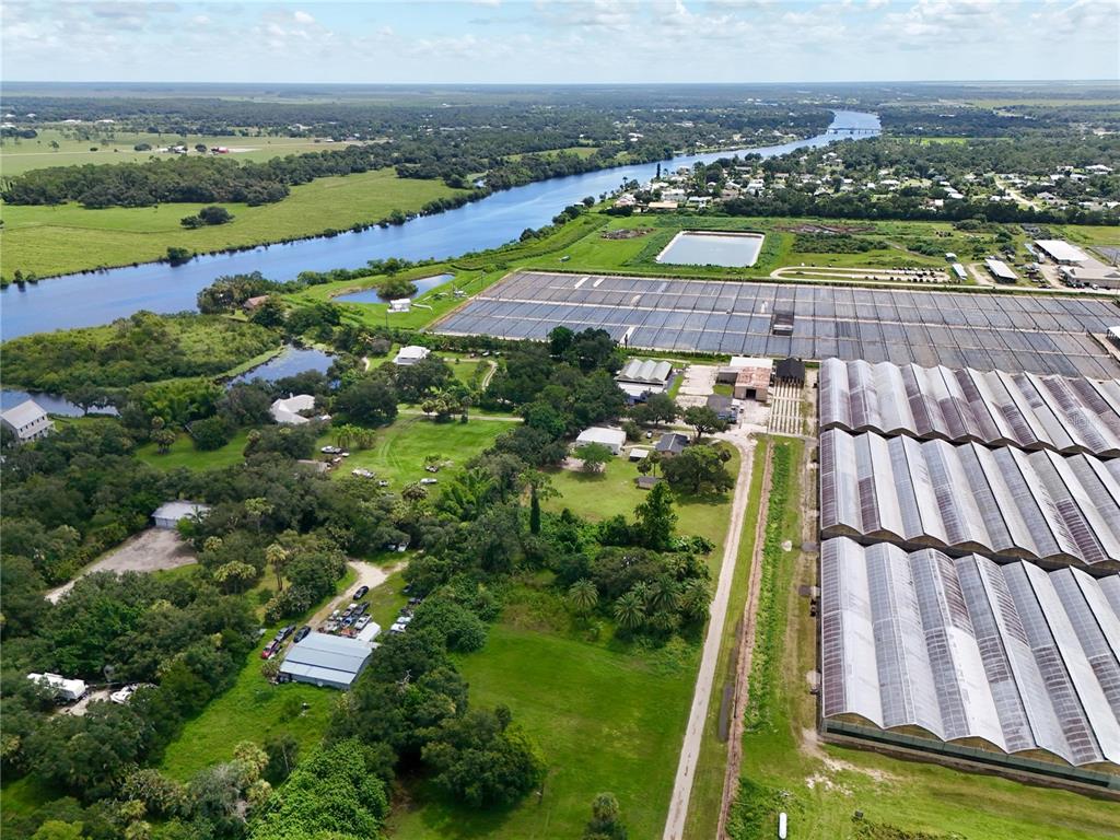 An aerial view shows a large greenhouse complex next to a river and rural landscape — 20101 WAGNER AVENUE, ALVA, FL