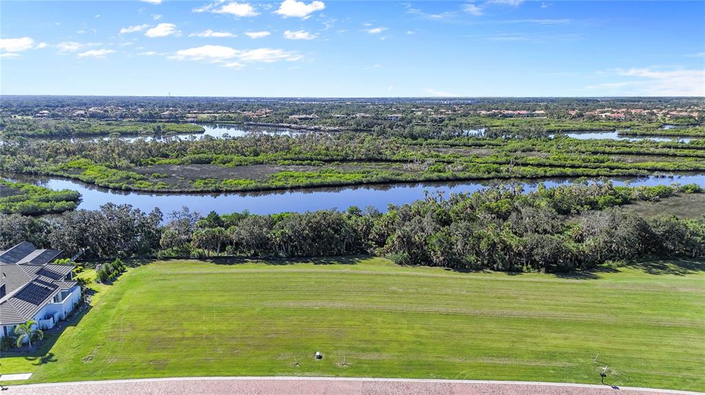 An aerial view of a vacant grassy lot bordering a river and dense vegetation — 1632 RIO VISTA TERRACE, PARRISH, FL