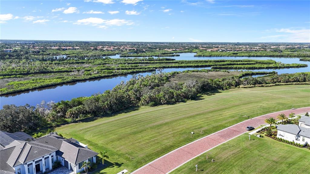 An aerial view shows a vacant grassy lot next to a house and wetlands — 1632 RIO VISTA TERRACE, PARRISH, FL