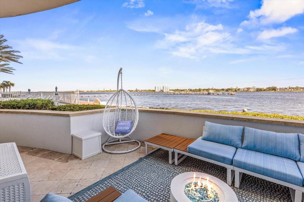 A patio overlooking a body of water features a fire pit, seating, and a hanging chair — 231 RIVERSIDE DRIVE UNIT 102, HOLLY HILL, FL