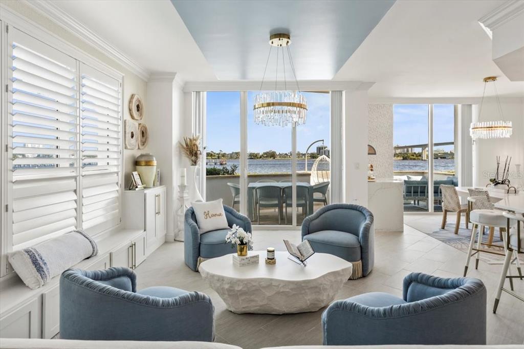 A bright living area features blue armchairs, a stone coffee table, and waterfront balcony views — 231 RIVERSIDE DRIVE UNIT 102, HOLLY HILL, FL