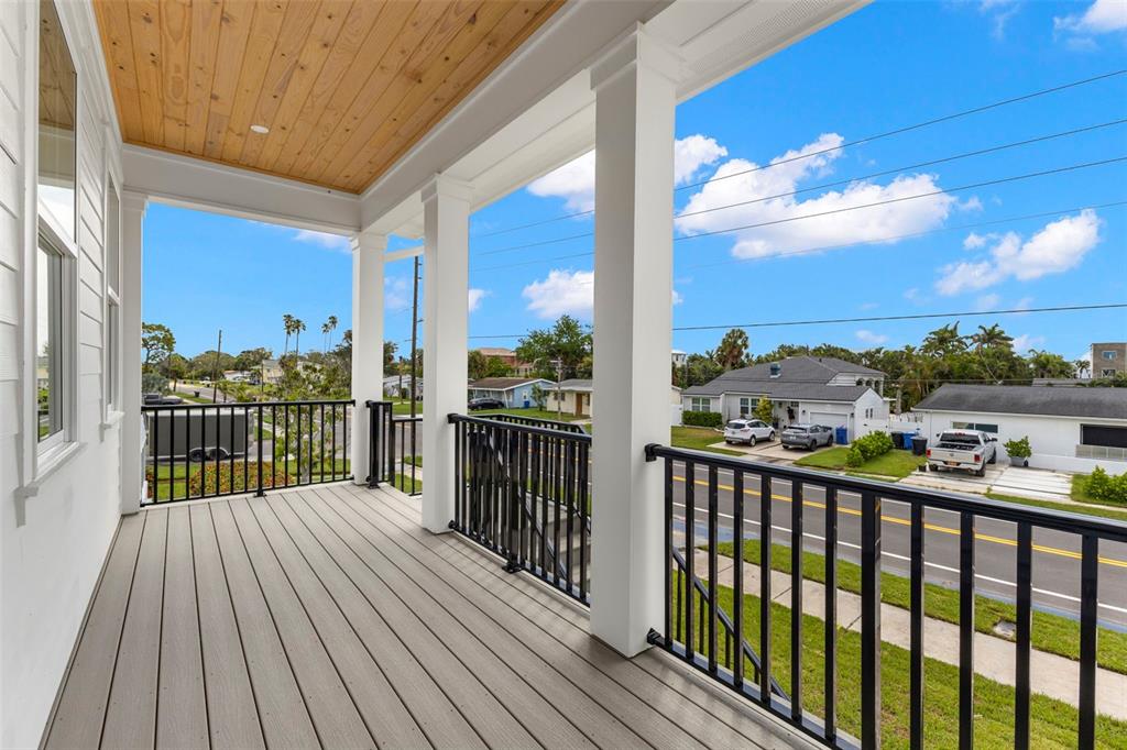 A covered balcony with wood-paneled ceiling, gray composite decking, and black metal railings — 3534 OVERLOOK DRIVE NE, ST PETERSBURG, FL