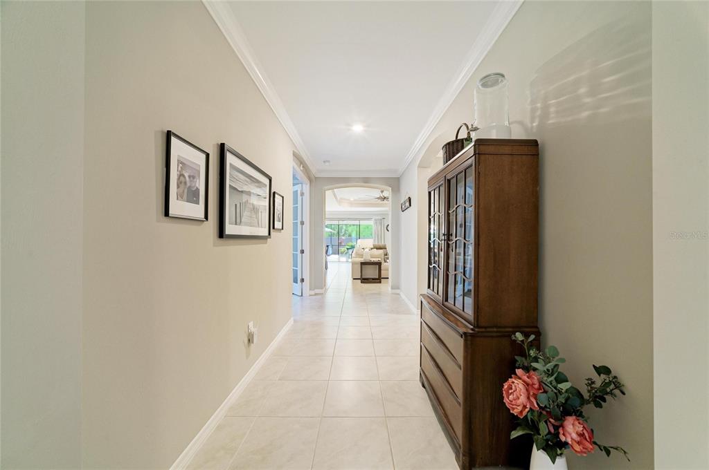 A hallway with light tile flooring leads toward a living area with a ceiling fan — 174 VERAZA COURT, NOKOMIS, FL