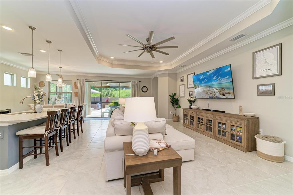 A bright open-concept living room features a large sectional sofa, a media console, and kitchen seating — 174 VERAZA COURT, NOKOMIS, FL