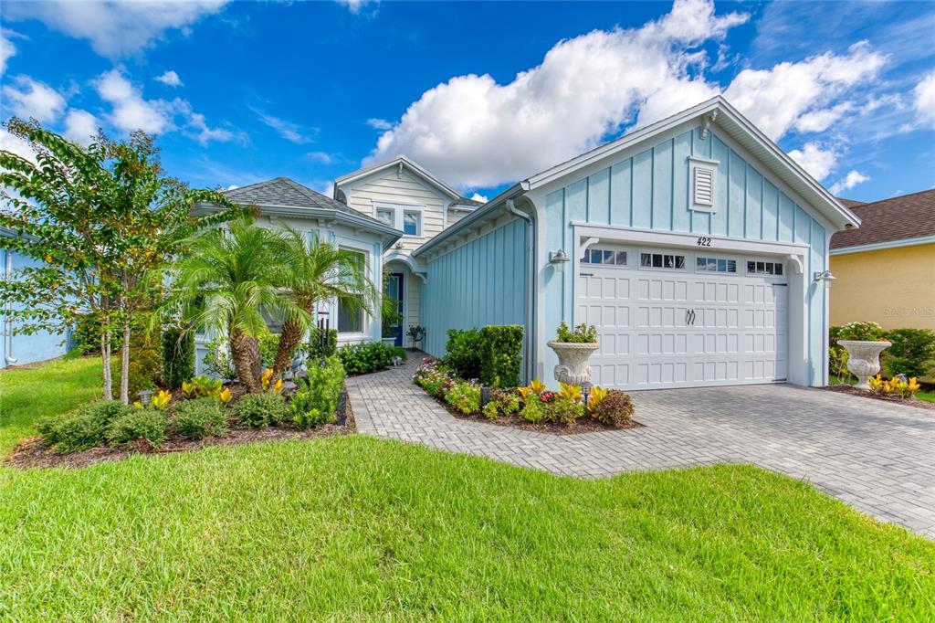 A light blue house with a paved walkway, a two-car garage, and a landscaped front yard — 422 CORAL REEF WAY, DAYTONA BEACH, FL