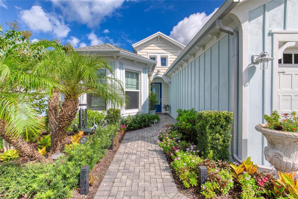 A paved walkway leads to the blue front door of a light blue house exterior — 422 CORAL REEF WAY, DAYTONA BEACH, FL