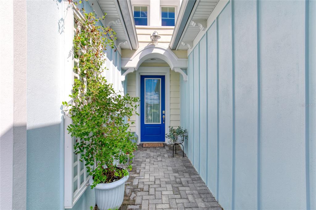 A blue front door sits at the end of a paved walkway with light blue siding — 422 CORAL REEF WAY, DAYTONA BEACH, FL