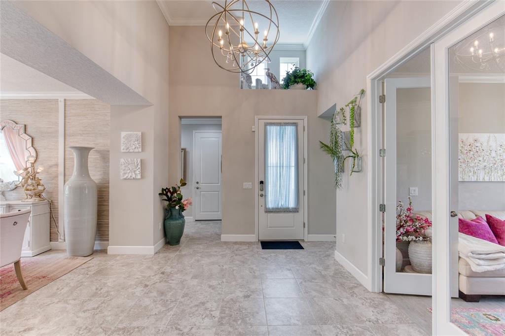 A bright foyer features tile flooring, a high ceiling with a chandelier, and glass-paneled doors — 422 CORAL REEF WAY, DAYTONA BEACH, FL
