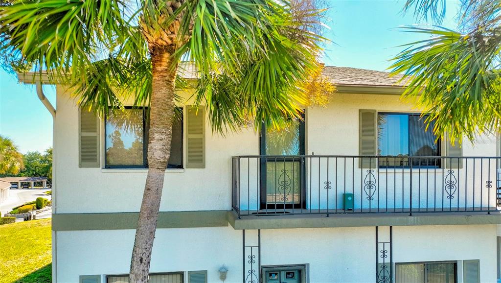 A two-story stucco building features a second-floor balcony with black railings and palm trees — 6502 RIVER RUN BOULEVARD, WEEKI WACHEE, FL