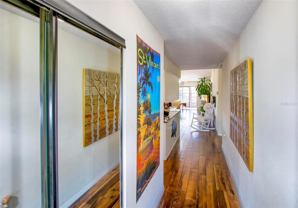 A hallway features wood-look flooring, a white front door, and large wall art — 6502 RIVER RUN BOULEVARD, WEEKI WACHEE, FL