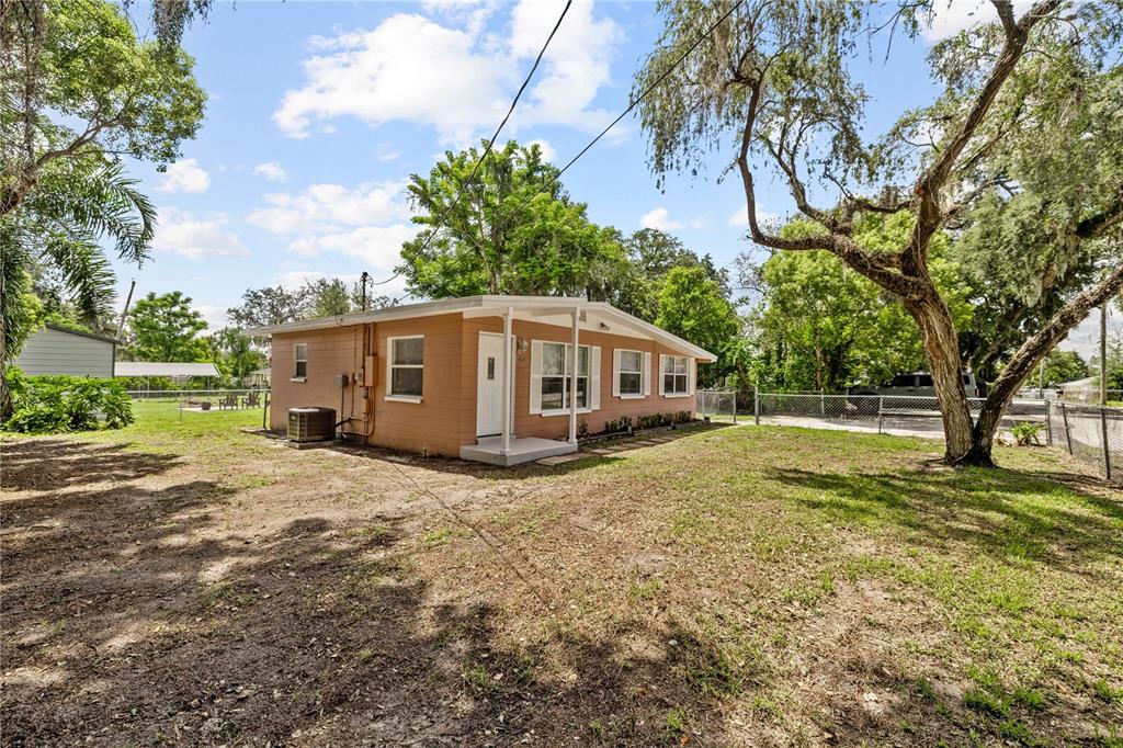 A tan, single-story house with a small covered porch sits on a grassy lot — 5225 PEACH AVENUE, SEFFNER, FL