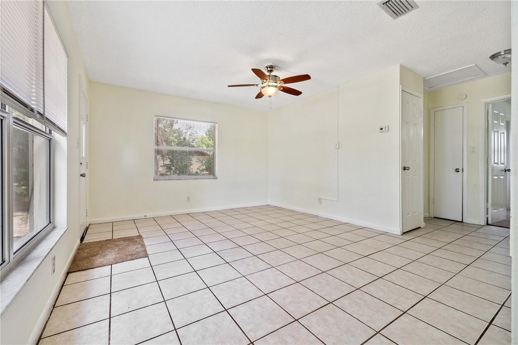 An empty room with light-colored tile flooring, a ceiling fan, and white walls — 5225 PEACH AVENUE, SEFFNER, FL