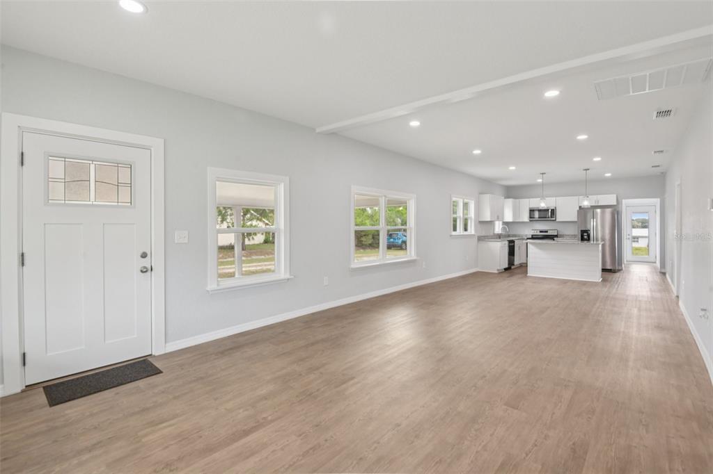 A bright, open-concept living area features light wood-look flooring and a modern white kitchen — 3070 E CENTRAL AVENUE, BARTOW, FL