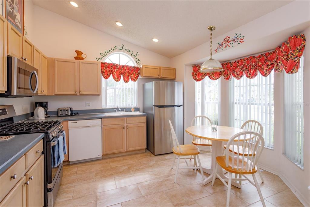 A kitchen with light wood cabinets, stainless steel appliances, and a small dining area — 4655 CHEYENNE POINT TRAIL, KISSIMMEE, FL