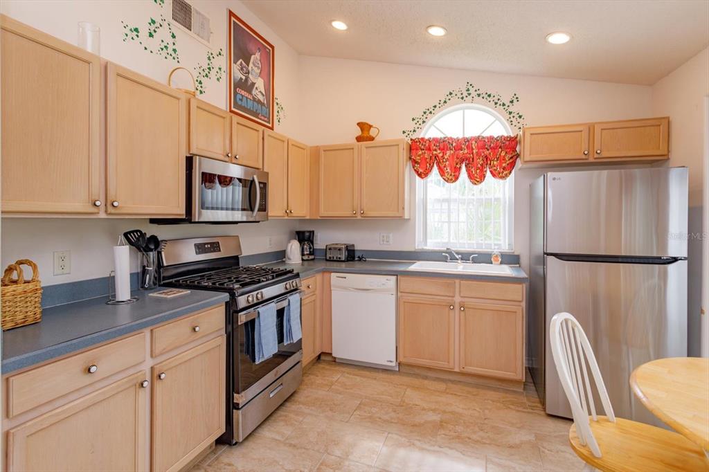 A kitchen features light wood cabinets, stainless steel appliances, blue countertops, and a tiled floor — 4655 CHEYENNE POINT TRAIL, KISSIMMEE, FL