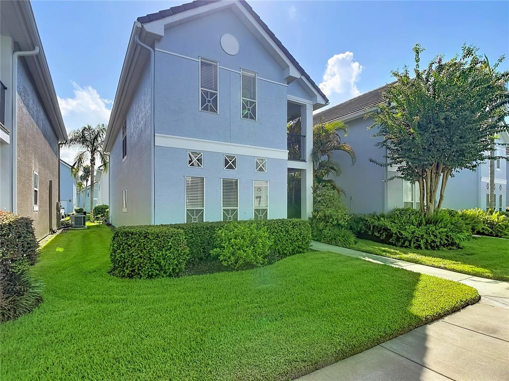A light blue two-story house with a manicured lawn and a sidewalk in front — 4008 BANGALOW PALM COURT, TAMPA, FL