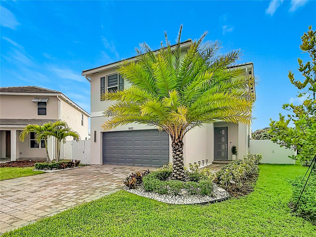 A two-story house with a gray garage, a palm tree, and a paved driveway — 1692 SE 7TH COURT, HOMESTEAD, FL
