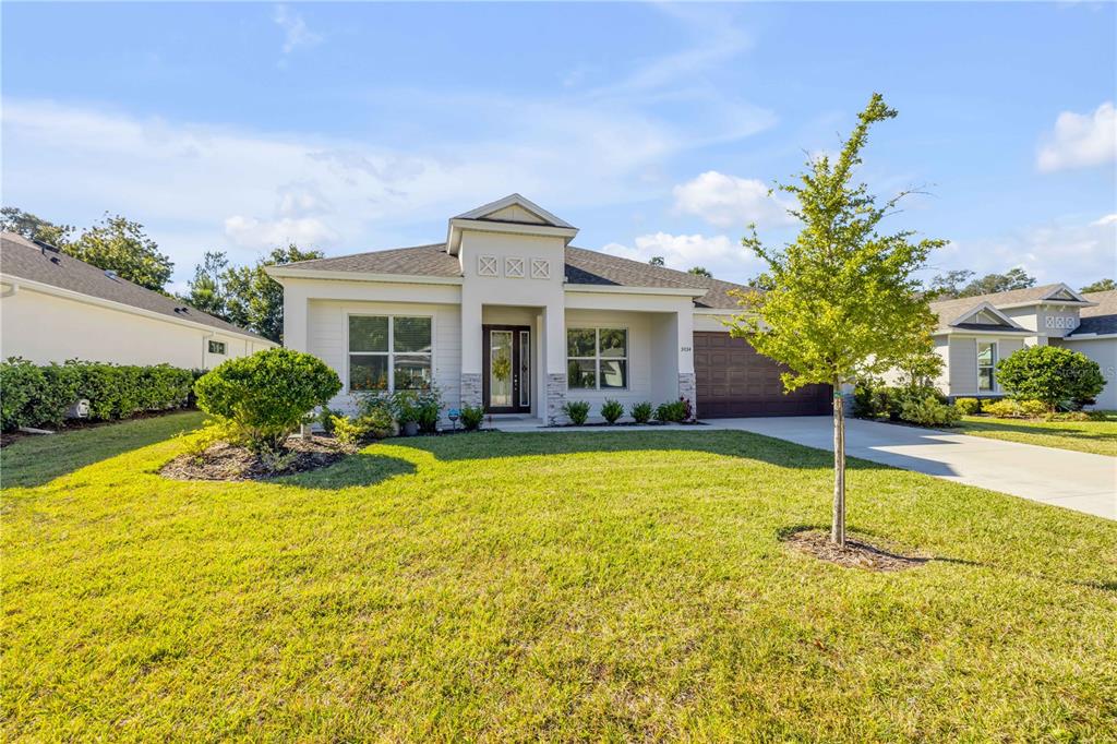 A single-story suburban house with a brown garage door, light siding, and a manicured lawn — 3034 ADRIAN DRIVE, ORMOND BEACH, FL