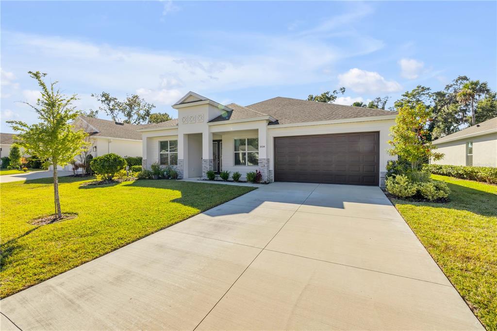 A single-story house with a beige exterior, stone accents, and a two-car garage — 3034 ADRIAN DRIVE, ORMOND BEACH, FL