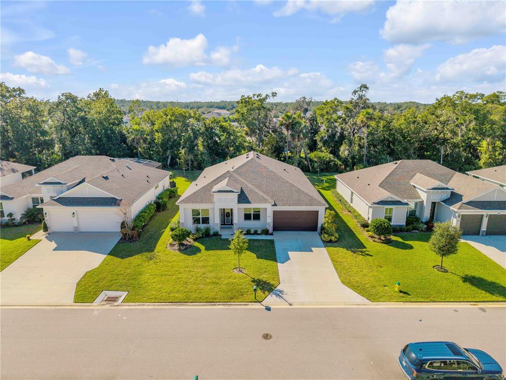 An aerial view shows three suburban houses with driveways and lawns under a blue sky — 3034 ADRIAN DRIVE, ORMOND BEACH, FL
